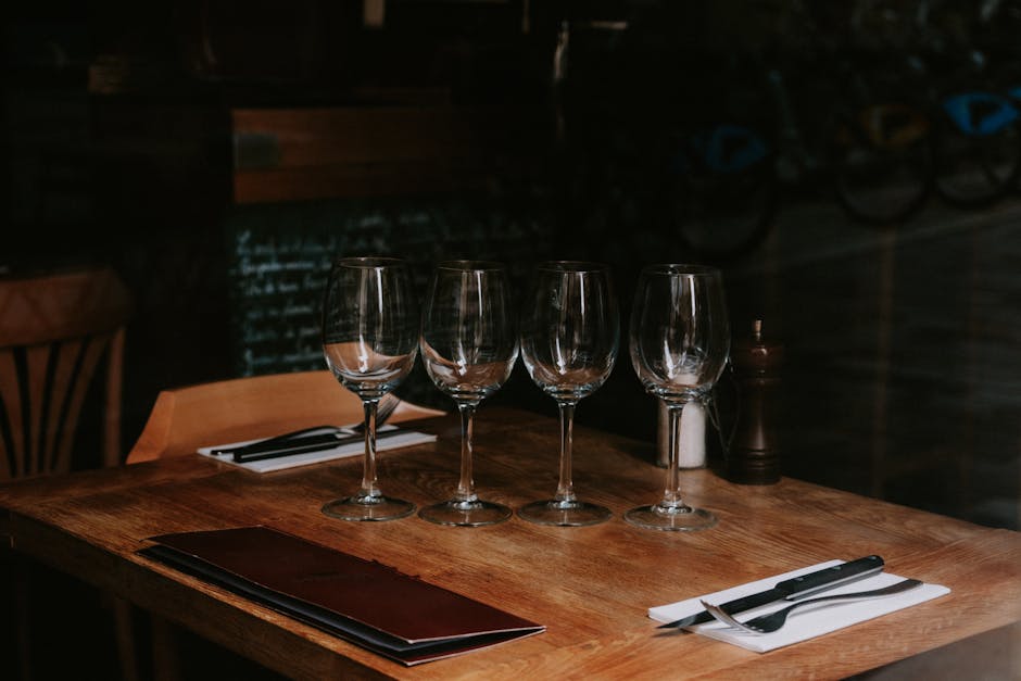Uredno uređen stol s čašama za vino i priborom za jelo u prigušeno osvijetljenom restoranu